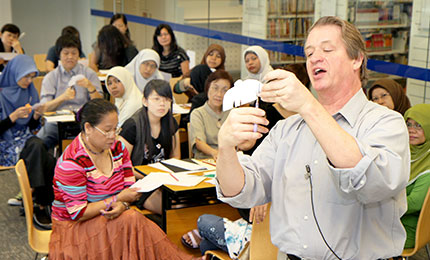 Randel demonstrates paper crafts for a class